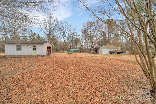 view of yard with a detached garage, an outbuilding, and an outdoor structure