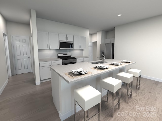 kitchen featuring stainless steel appliances, sink, a kitchen breakfast bar, light hardwood / wood-style floors, and a center island with sink