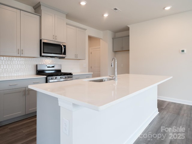 kitchen with stainless steel appliances, a center island with sink, sink, and gray cabinets