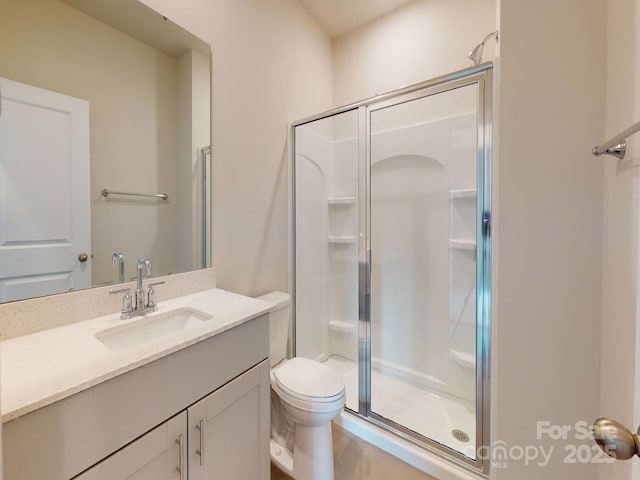 bathroom featuring toilet, a shower with door, and vanity