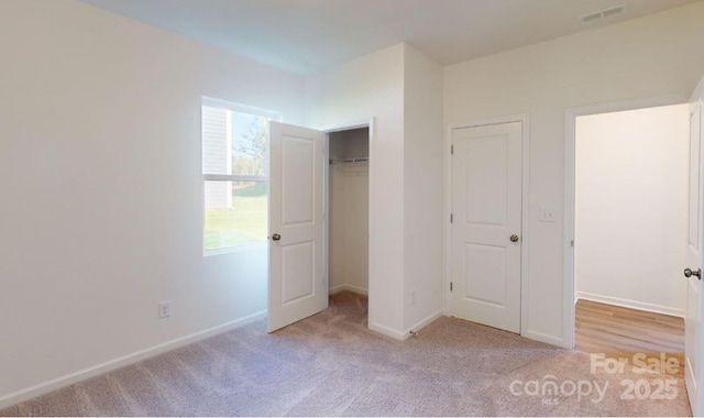 unfurnished bedroom featuring light carpet and a closet