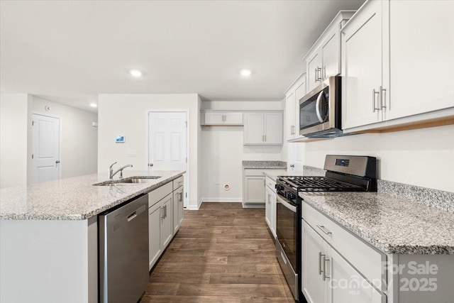 kitchen featuring white cabinetry, a center island with sink, appliances with stainless steel finishes, light stone counters, and sink