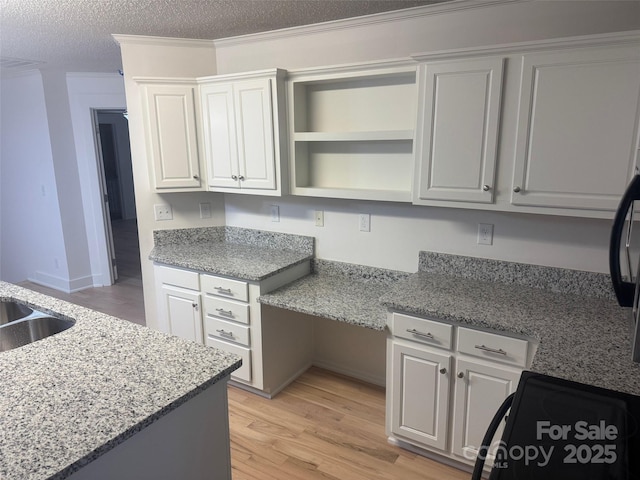 kitchen with light stone countertops, ornamental molding, a textured ceiling, light hardwood / wood-style floors, and range