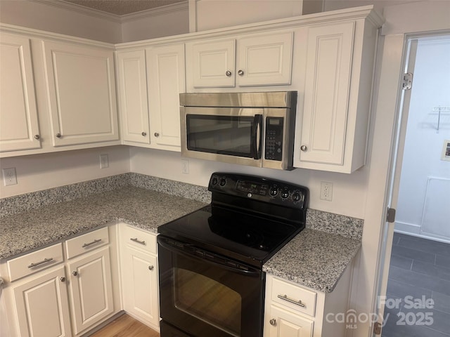 kitchen with electric range, white cabinets, light stone countertops, and ornamental molding