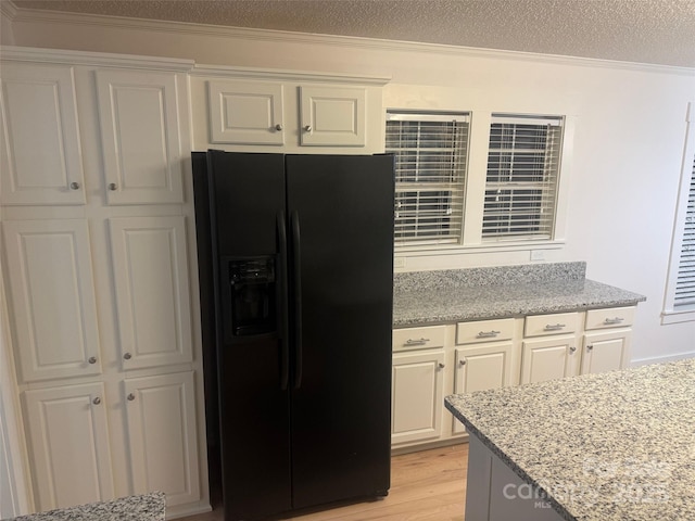 kitchen featuring light stone countertops, black fridge, white cabinetry, and a textured ceiling