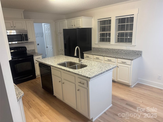 kitchen with black appliances, a center island with sink, sink, light stone countertops, and white cabinetry