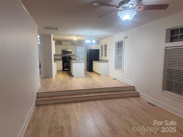 kitchen with crown molding, white cabinetry, hanging light fixtures, and black appliances