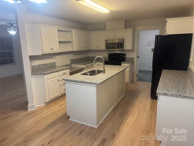 kitchen with a textured ceiling, sink, black appliances, white cabinets, and an island with sink