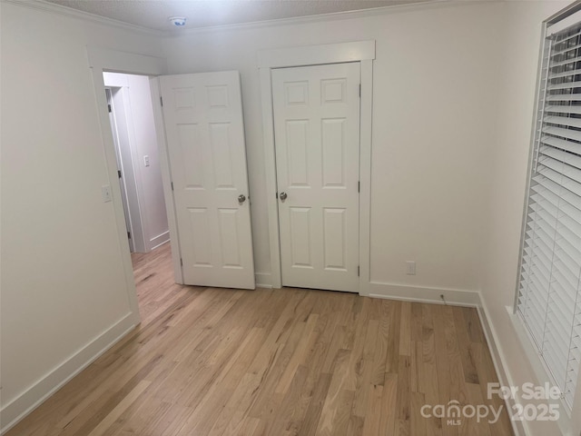 unfurnished bedroom with light hardwood / wood-style floors, a closet, and ornamental molding