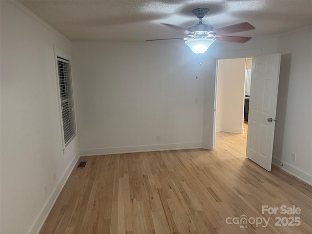 empty room featuring ornamental molding, a textured ceiling, and light wood-type flooring