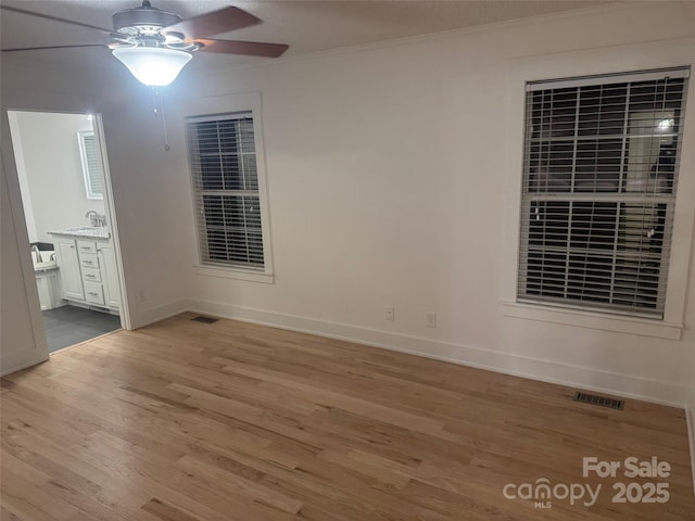 empty room featuring light hardwood / wood-style floors, ceiling fan, crown molding, and sink