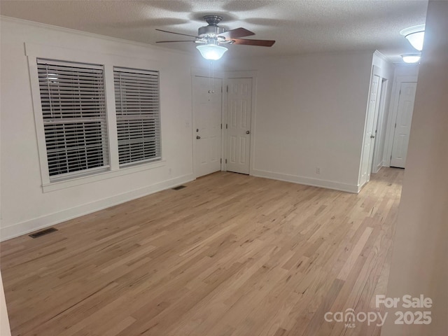 empty room featuring ceiling fan, light wood-type flooring, and a textured ceiling