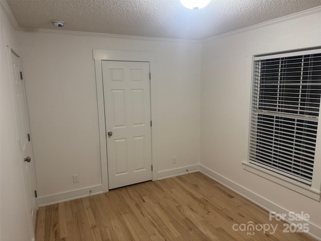 unfurnished bedroom with light hardwood / wood-style floors, ornamental molding, and a closet