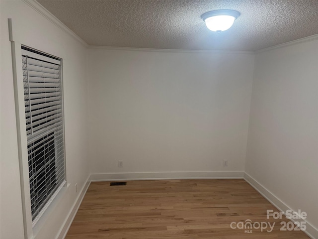 unfurnished room featuring light hardwood / wood-style floors, ornamental molding, and a textured ceiling