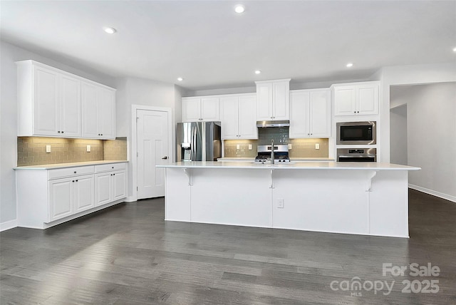 kitchen with a large island, a kitchen bar, white cabinetry, and appliances with stainless steel finishes