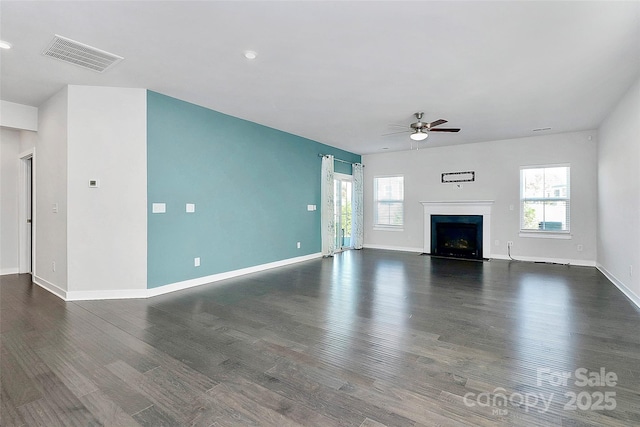 unfurnished living room with plenty of natural light, ceiling fan, and dark hardwood / wood-style flooring