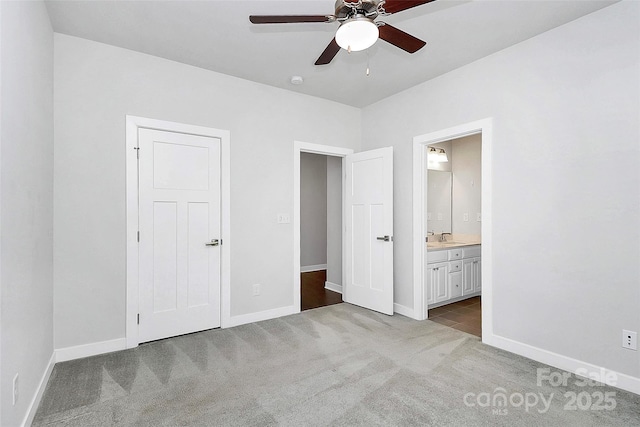 unfurnished bedroom featuring ensuite bathroom, ceiling fan, light colored carpet, and sink