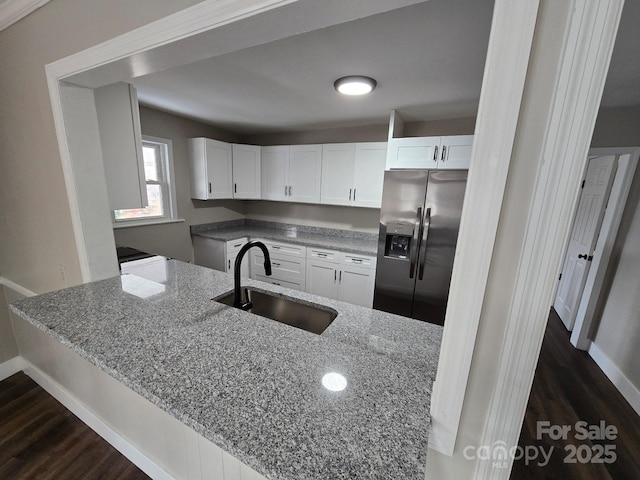 kitchen with light stone counters, sink, white cabinets, and stainless steel refrigerator with ice dispenser