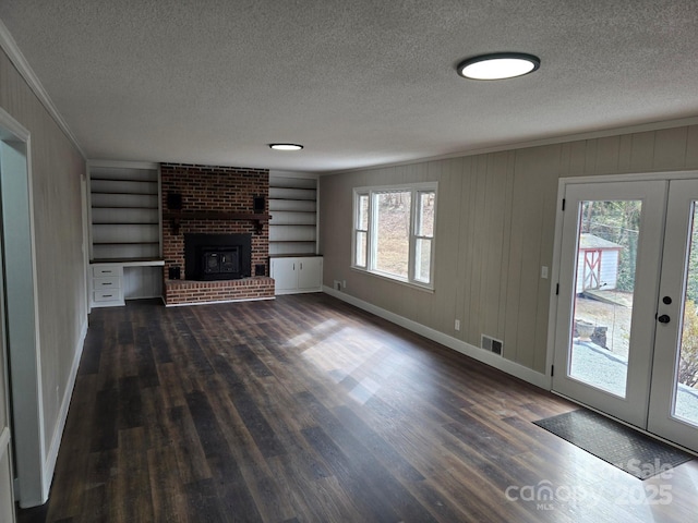 unfurnished living room featuring built in shelves, a textured ceiling, french doors, and a wealth of natural light