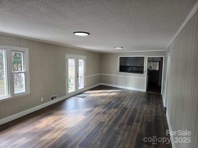 unfurnished living room featuring crown molding, dark hardwood / wood-style floors, french doors, and wood walls