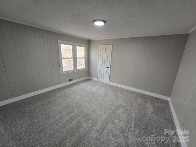 unfurnished room featuring ornamental molding, wooden walls, carpet floors, and a textured ceiling