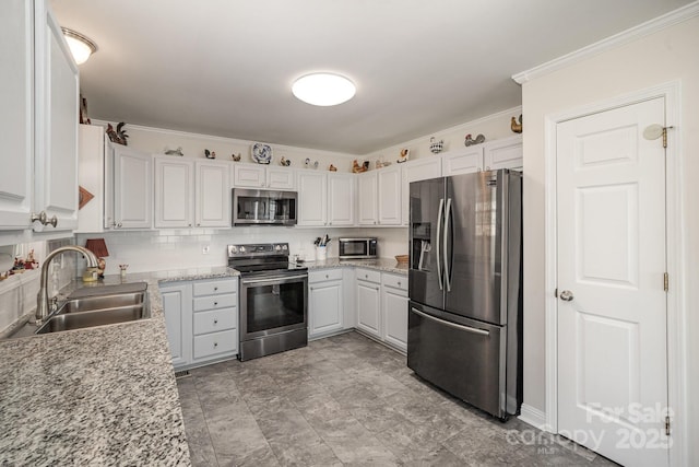 kitchen featuring backsplash, sink, appliances with stainless steel finishes, white cabinets, and light stone counters