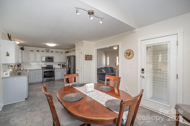 dining space featuring ceiling fan, sink, and crown molding