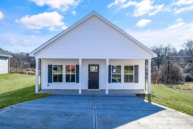 rear view of house featuring a lawn and covered porch