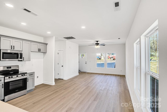 kitchen with appliances with stainless steel finishes, light wood-type flooring, backsplash, ceiling fan, and gray cabinets