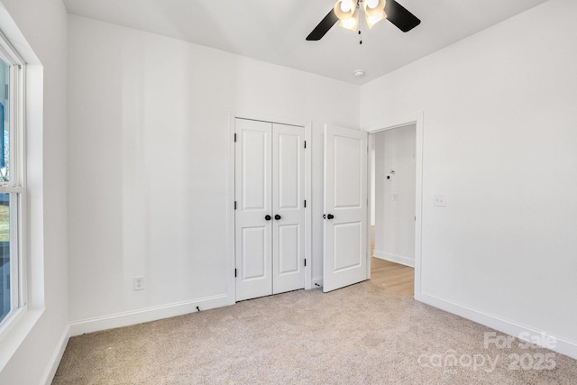 unfurnished bedroom with a closet, light colored carpet, and ceiling fan