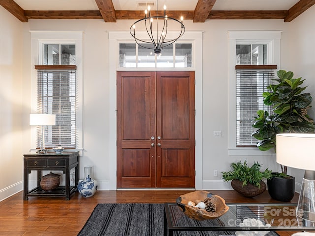 entrance foyer with beam ceiling, dark wood-type flooring, and a chandelier