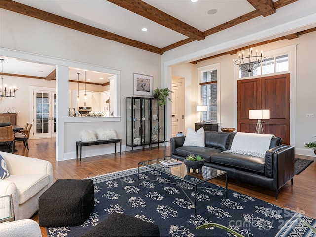 living room featuring wood-type flooring, ornamental molding, and a notable chandelier