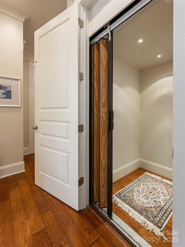 corridor featuring crown molding, a barn door, and wood-type flooring