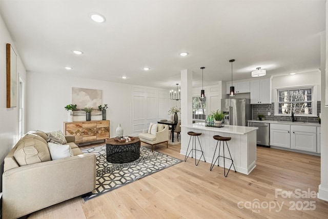 living room with recessed lighting, a notable chandelier, and light wood-style flooring