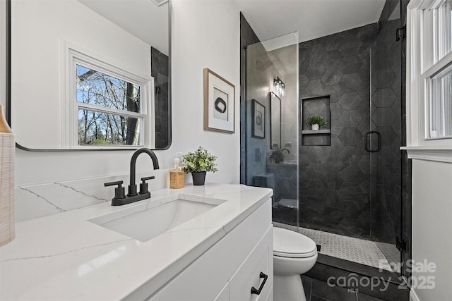 bathroom with toilet, an enclosed shower, and vanity