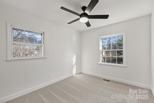 carpeted spare room with ceiling fan and plenty of natural light