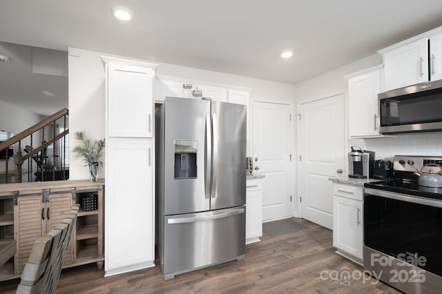 kitchen with appliances with stainless steel finishes, dark hardwood / wood-style flooring, white cabinets, light stone countertops, and backsplash