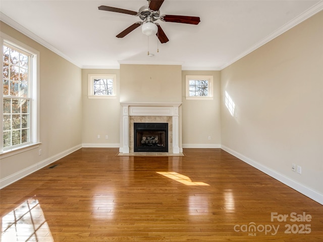 unfurnished living room featuring a healthy amount of sunlight, crown molding, and a tile fireplace