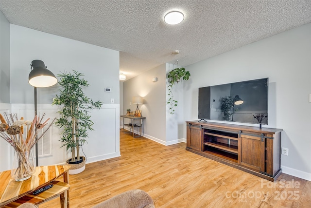 living room with a textured ceiling and light hardwood / wood-style floors