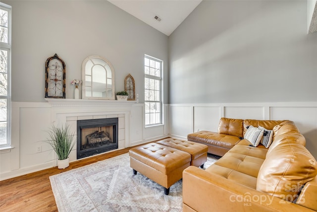 living room with wood-type flooring, high vaulted ceiling, and a fireplace