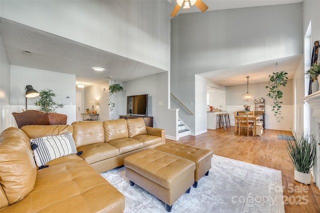 living room with a high ceiling, light wood-type flooring, and ceiling fan