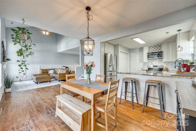 dining room with a textured ceiling, light wood-type flooring, and a chandelier