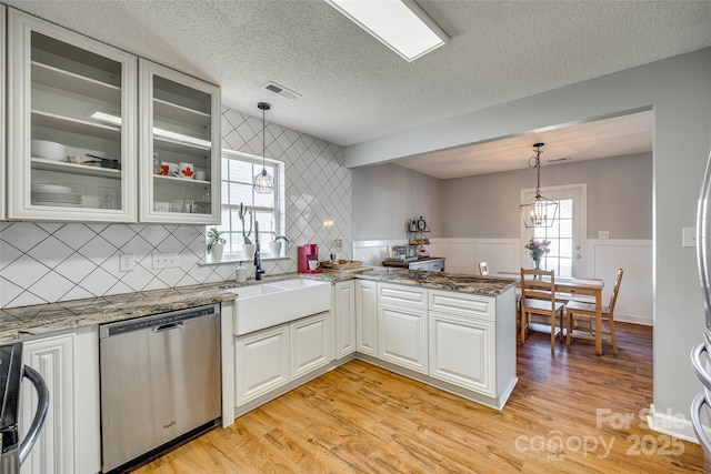 kitchen with stainless steel dishwasher, white cabinetry, a textured ceiling, and hanging light fixtures