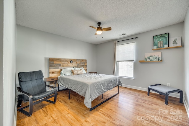 bedroom with ceiling fan, light hardwood / wood-style floors, and a textured ceiling