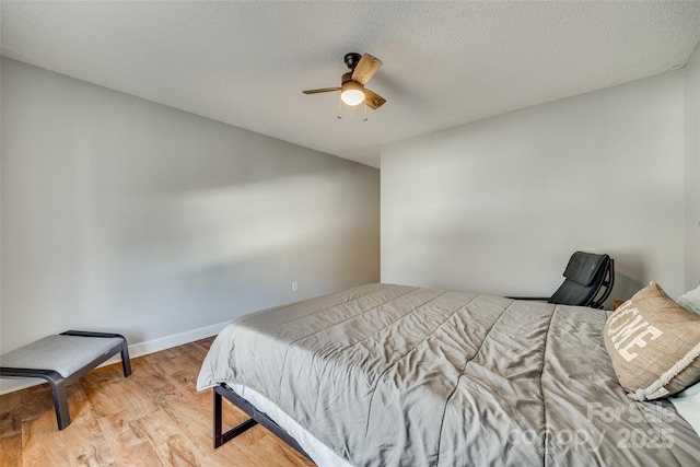 bedroom featuring ceiling fan, light wood-type flooring, and a textured ceiling