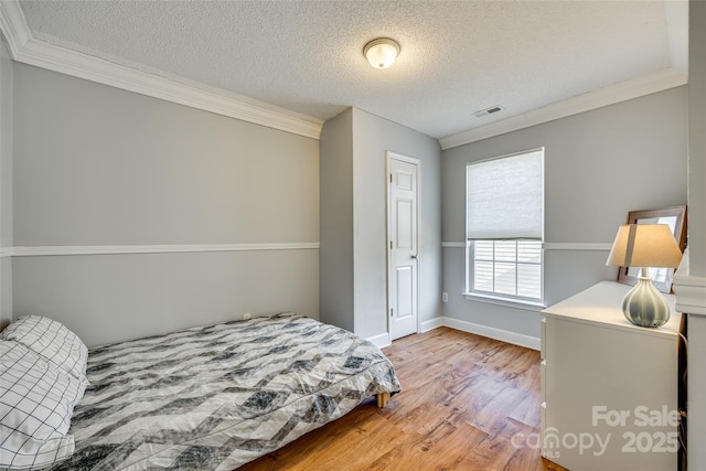 bedroom with a textured ceiling, light hardwood / wood-style floors, and ornamental molding