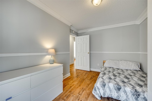 bedroom with a textured ceiling, light hardwood / wood-style floors, and crown molding