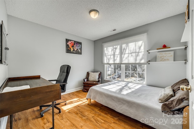 bedroom with a textured ceiling and hardwood / wood-style floors