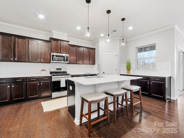 kitchen with sink, decorative light fixtures, a kitchen bar, a kitchen island with sink, and appliances with stainless steel finishes