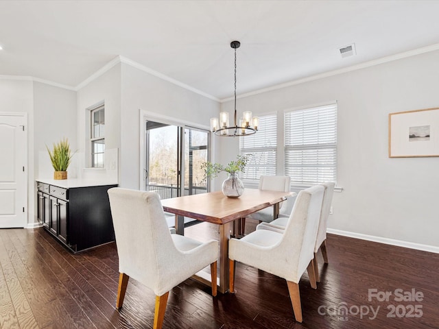 dining room with an inviting chandelier, crown molding, and dark hardwood / wood-style floors